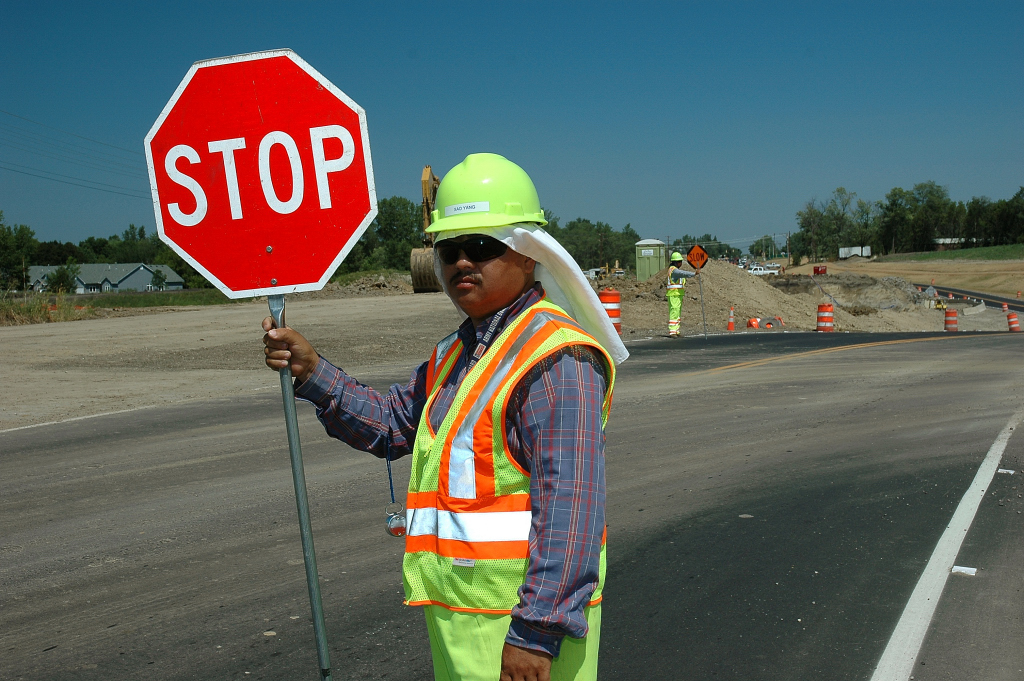MnDOT employee at work site using a stop sign to control traffic