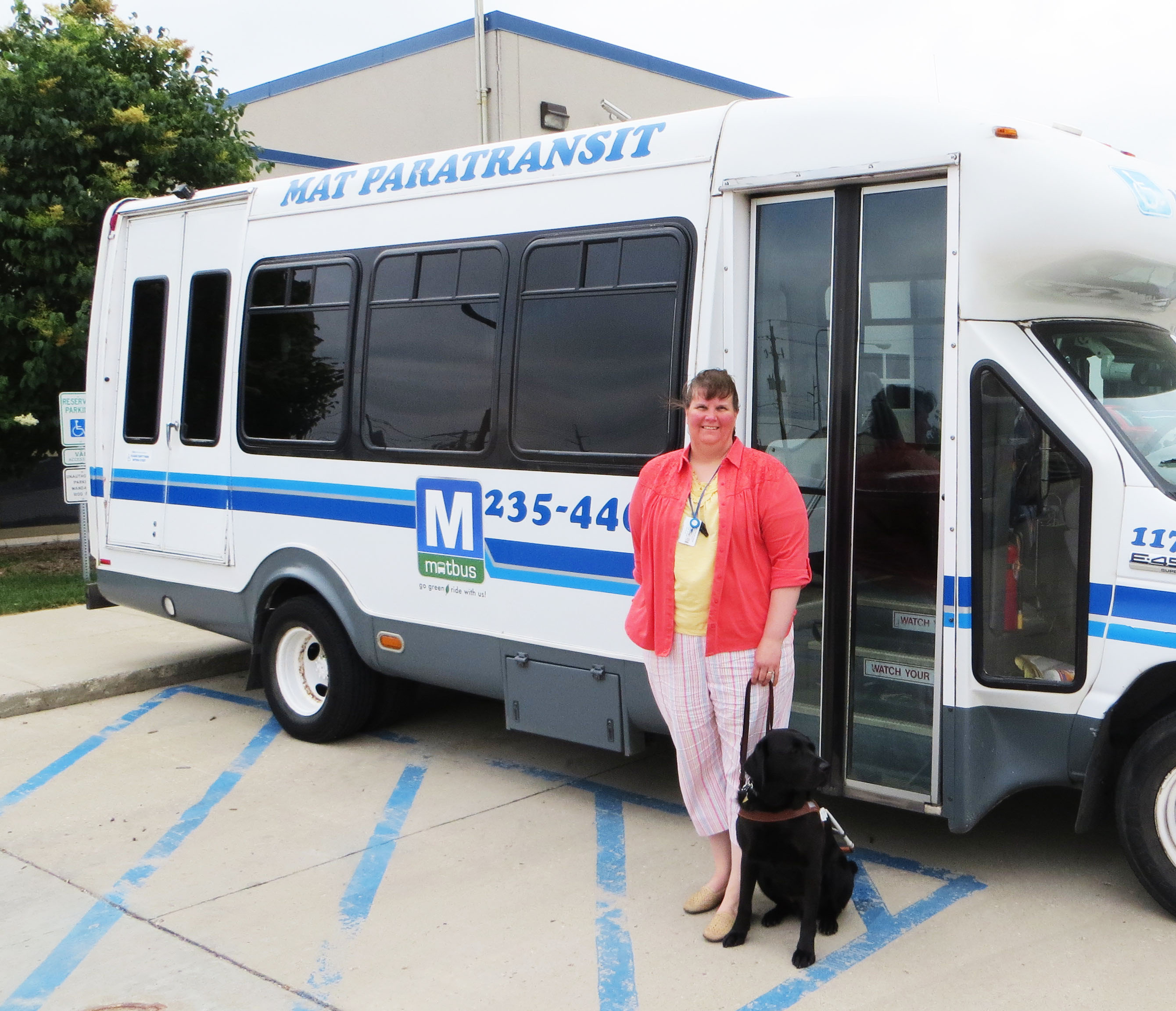 Paratransit user standing in front of paratransit bus